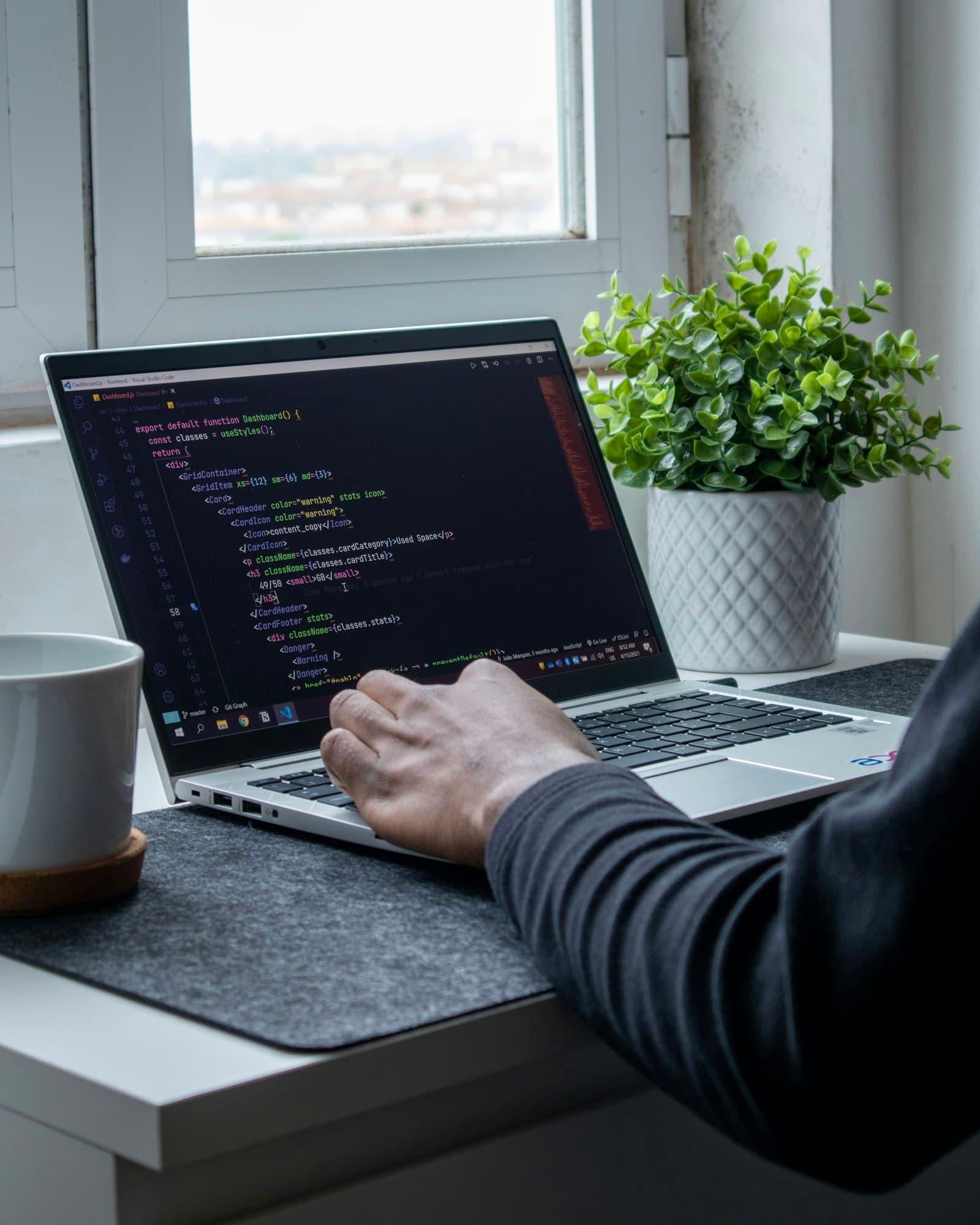 Hands working on a laptop with a code editor